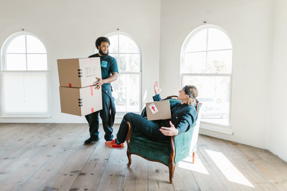 Inside a residential property during a home relocation, a moving process is underway with several cardboard boxes of varying sizes stacked on the floor near a doorway. Some boxes are sealed with packi